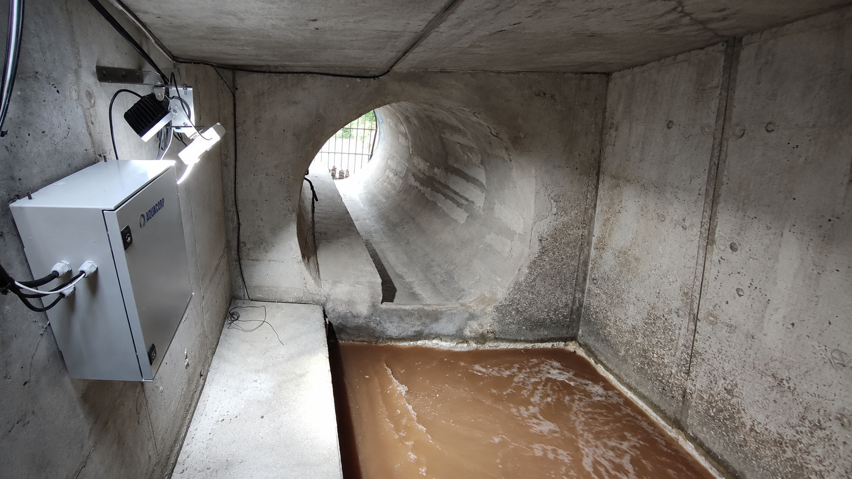 Equipo óptico y foco de Aquacorp junto al agua de un canal de saneamiento